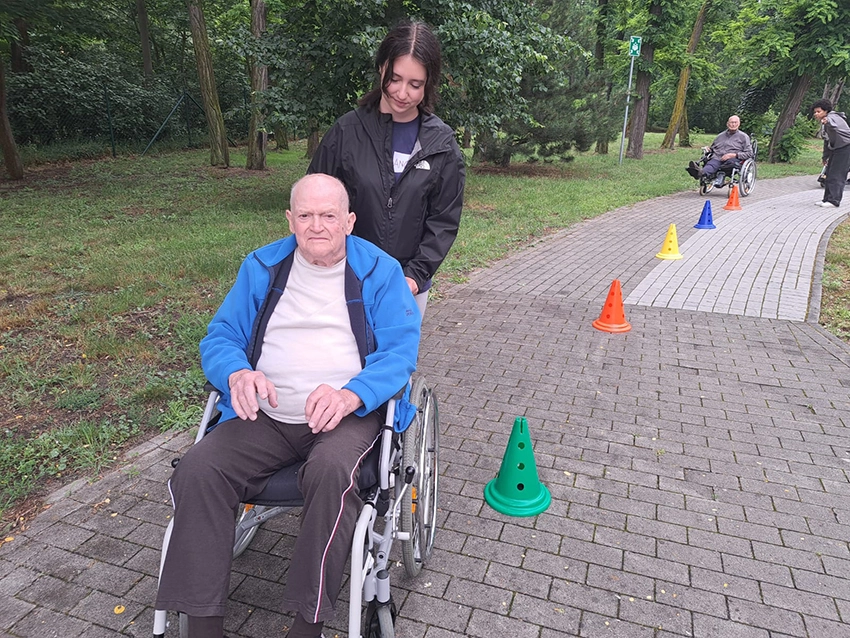 Schülerin schiebt Mann im Rollstuhl durch Parcours