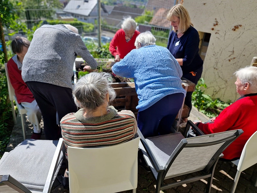 Bewohnerinnen und Bewohner beim Pflanzen am Hochbeet