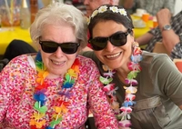 Mit Blütenkranz und Sonnenbrille genießen die Bewohnerin und die Mitarbeiterin das Sommerfest im CentroVerde